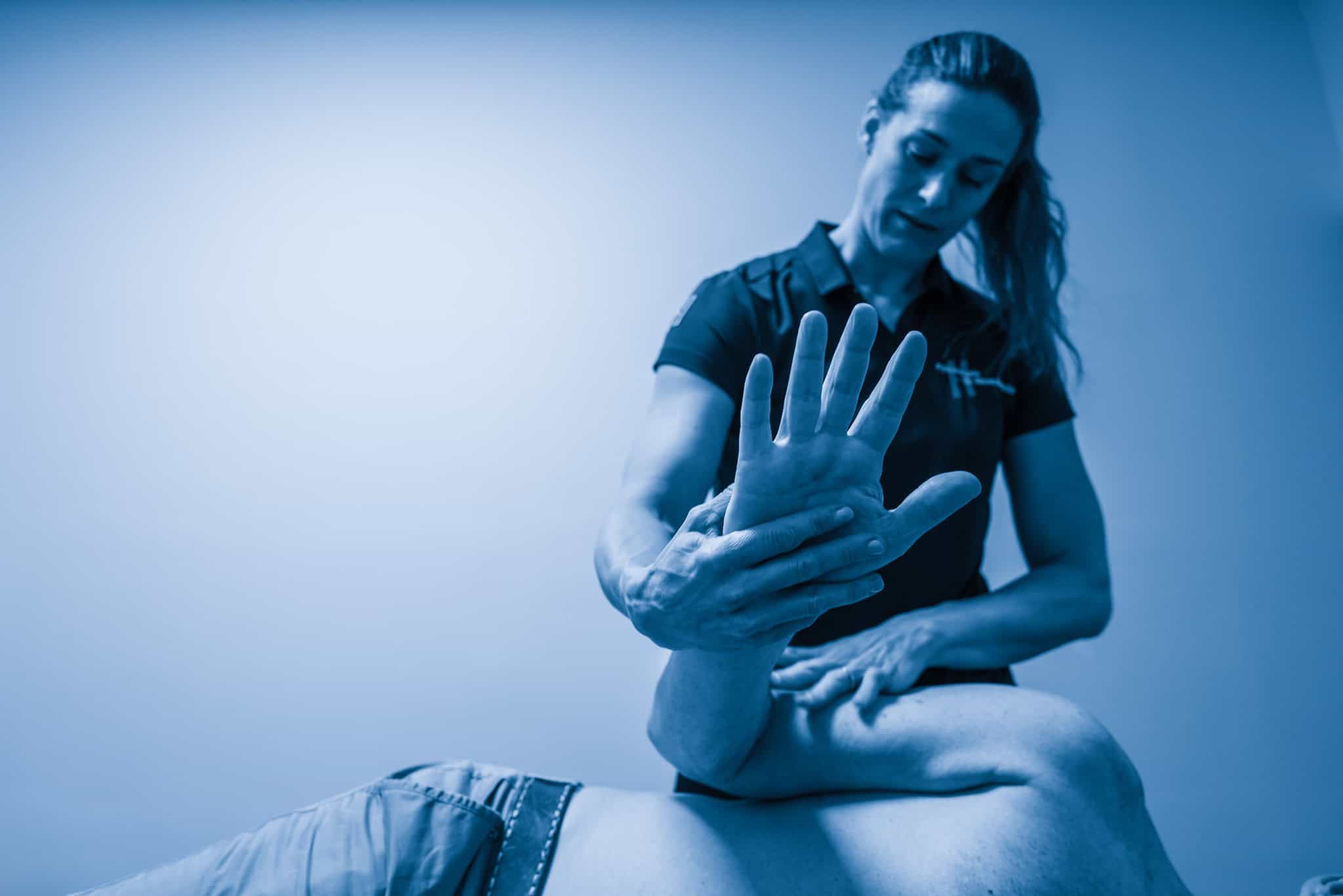 Fysiotherapeut behandelt hand en pols met therapeutische technieken in praktijkruimte. specialisaties